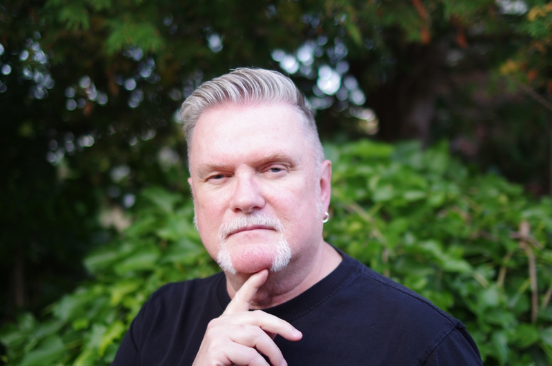 Portrait of David Moulton Counsellor for Toronto looking intently curious standing in front of a mulberry bush