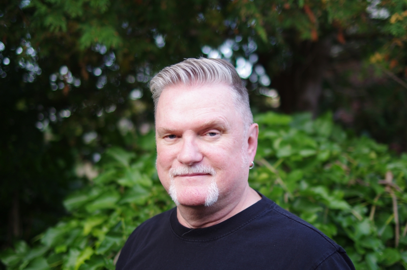 Portrait of David Moulton Counsellor for Toronto with his eyebrow raised standing in front of a mulberry bush